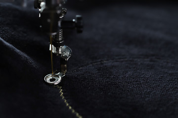 Detail view on needle of embroidery machine piercing in black velvetely fabric to stitch underlay...