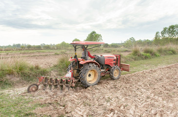 Fototapeta premium Tractor working plows a field on the farm for planting
