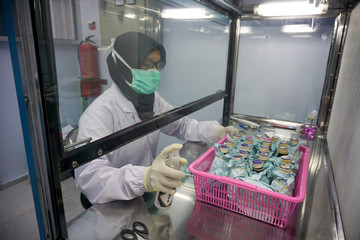 chemist spray sterilization liquid to glass bottles of water sample inside laminar