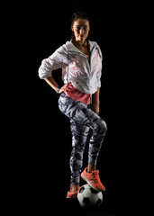 Naklejka premium Sport woman on dark background holding a soccer ball