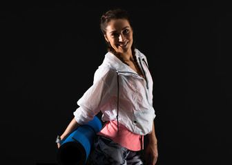 Sport woman on dark background with mat