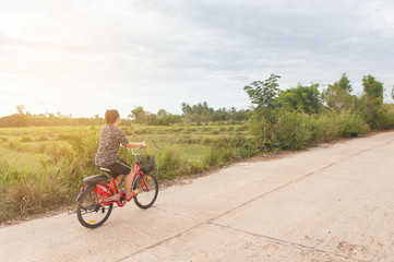 Woman riding bicycle relax in a country road.