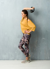 Sport woman over grunge wall making weightlifting