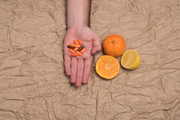 Image of a set of fruits tangerines and lemon and a handful of pills. Mandarins and orange pills.