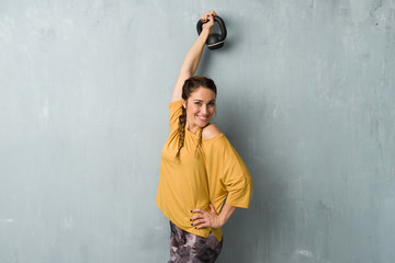 Fototapeta na wymiar Sport woman over grunge wall making weightlifting