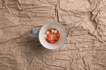 Multicolored pills in a mug. Studio image of a lot of tablets in a cup. Tablets, vitamins, capsules, medicament.
