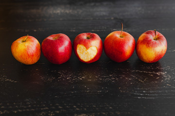 group of red apples with different tones on dark wooden table