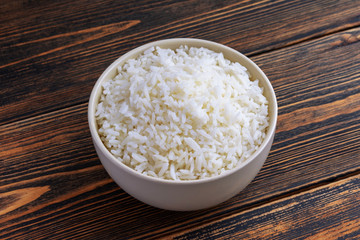 A Cup of white rice on a dark wooden background. Dietary or vegetarian food. Food cooked at home.