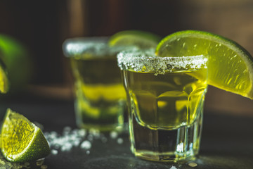 Mexican Gold Tequila shot with lime and salt on black stone table surface