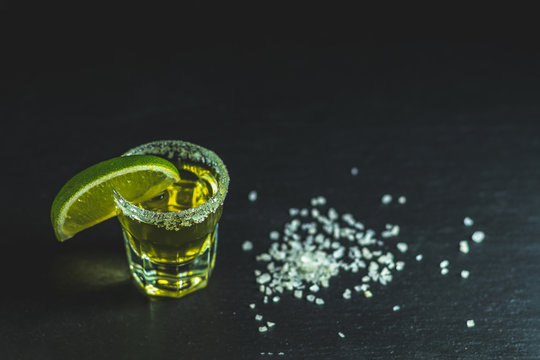 Mexican Gold Tequila Shot With Lime And Salt On Black Stone Table Surface