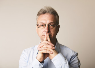 Serious senior man in glasses thinking over background