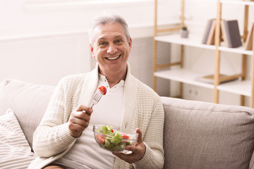 Happy senior man eating fresh vegetable salad