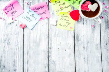 Valentines day concept, stickers with traditional valentine wishes, hot chocolate with marshmallow hearts and sugar sprinkles, old wooden background copy space banner