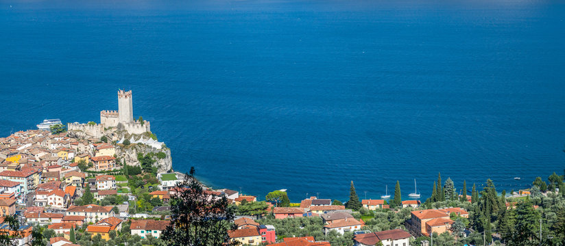 Idyllic coastline in Italy: Blue water and a cute village at lago di garda, Malcesine, sunset
