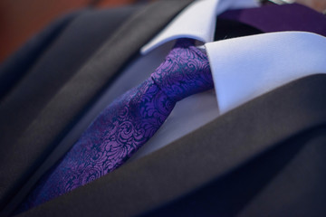 Close-up elegant suit with white shirt and purple silk necktie tied in a Windsor knot in preparation for a formal event, job interview or a wedding ceremony, or as part of office attire