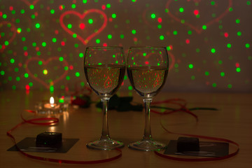 Two glasses with white wine , a candle, a rose and a red ribbon. Meeting