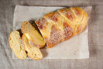 Fresh sliced challah jewish bread on paper over linen cloth