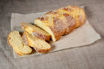Fresh sliced challah jewish bread on paper over linen cloth