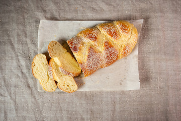 Fresh sliced challah jewish bread on paper over linen cloth