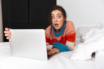 Attractive cheerful young woman laying on bed at home