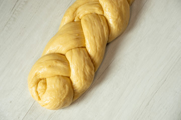 Raw loaf of challah jewish bread on wooden background. Top view flat lay.