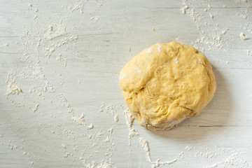Dough for traditional bread cooking on light wooden background, copy text. Top view, flat.
