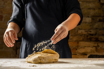 Close view of baker hands kneading dough for traditional bread. Food recipe concept.