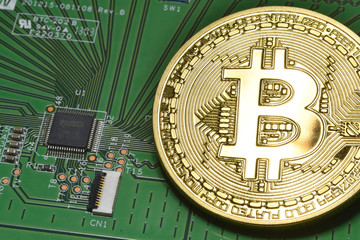 phisical gold bitcoin over electronic circuit board