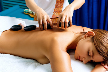 Obraz na płótnie Canvas Thai therapist doing massage with hot stones.