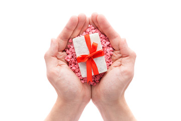 Hands holding little gift with red bow on a pile of candy hearts