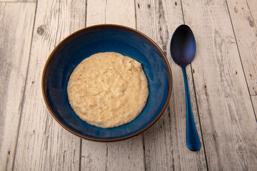 Bowl of plain porridge oats on a wooden table 