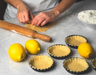 a process of making tartlets, female hands working with pastry dough