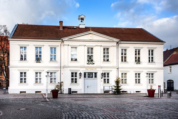 Germany, Prignitz, Pritzwalk: Panorama front view of town hall in the city center of the small German town with main entrance, public square and blue sky - concept administration. - obrazy, fototapety, plakaty