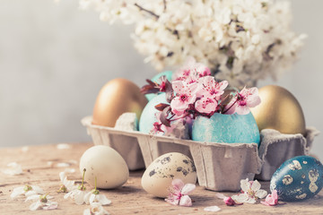 Easter eggs and spring flowers on wooden background. Easter holiday card copy space.