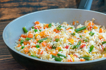 Roasted rice with vegetables in a ceramic pan with a small amount of oil.