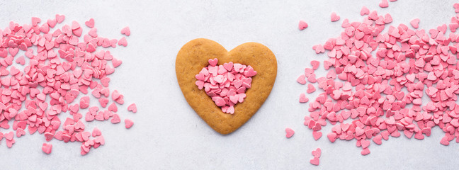 Heart shaped cookie and pink candy hearts for Valentine's Day.
