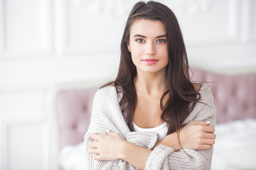 Young attractive woman indoors. Girl on neutral background. Happy woman. Female in the bedroom at home. Close up portrait of beautiful lady.