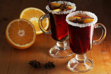 Two cups with ready mulled wine with anise, cinnamon and nuts around	