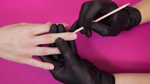 Manicurist handles cuticle with wooden sticks at the beauty salon, women's manicure, healthy nails, nail coating, nail treatment
