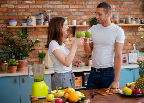 Young Couple Making Smoothie In Kitchen