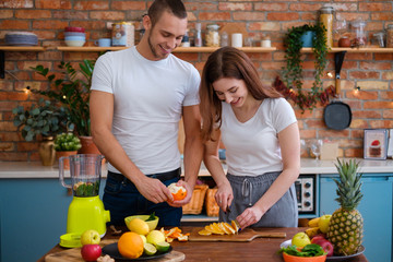 Young couple making smoothie in kitchen