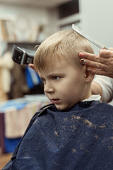 Little boy at the hairdresser. Child is scared of haircuts.