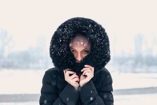 Woman wearing hoodie while snowing.