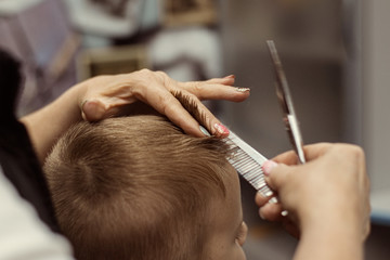 Little boy does a haircut at the hairdresser. Baby hair care.