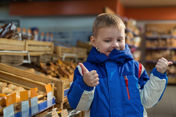 Little boy in a shop, supermarket, near the department for the sale of buns and bread.