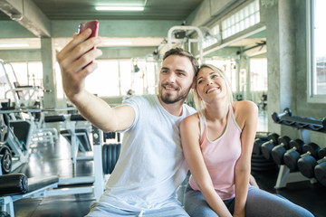Fototapeta na wymiar Caucasian sport couple take selfies photo after work out in gym