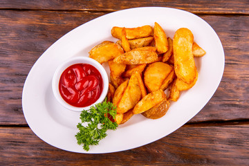Potato with a crust golden, is served with ketchup and greens