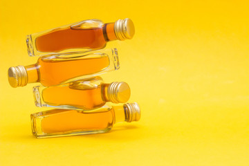 Small bottles with alcohol on a yellow background, close-up, copy space, export