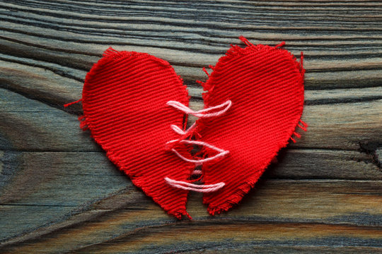 Repaired torn red heart on a wooden background