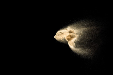 Golden sand explosion isolated on black background. Abstract sand cloud. Golden colored sand splash...